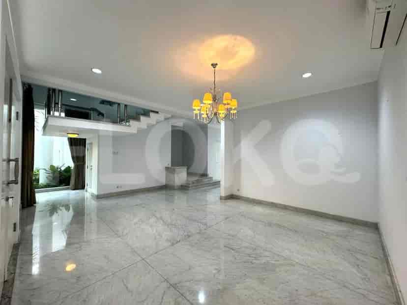 A well-lit living area featuring a staircase leading to the upper floor, marble flooring, and a chandelier.