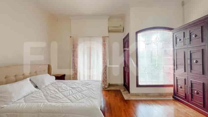 A bedroom with a bed, wardrobe, and curtains, featuring dark wooden flooring.