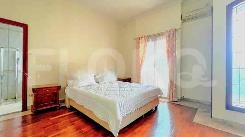 A bedroom with a bed, nightstand, and ensuite bathroom, featuring dark wooden flooring.
