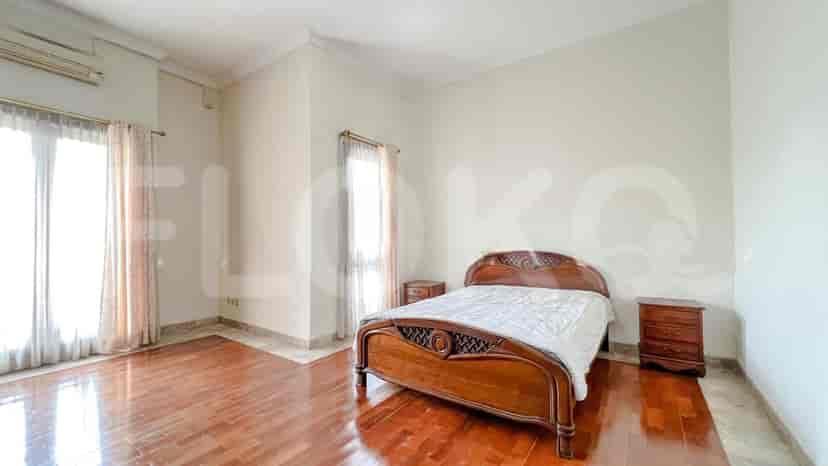 A bedroom with a bed, nightstands, and large windows, featuring dark wooden flooring.