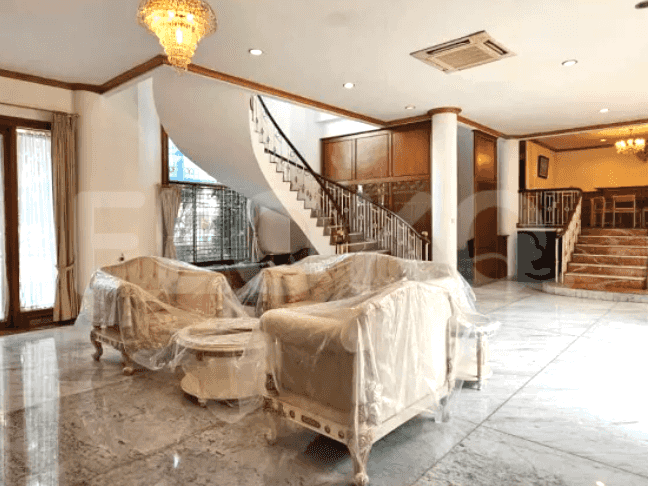 A large living room with sofas, a spiral staircase, and a chandelier.