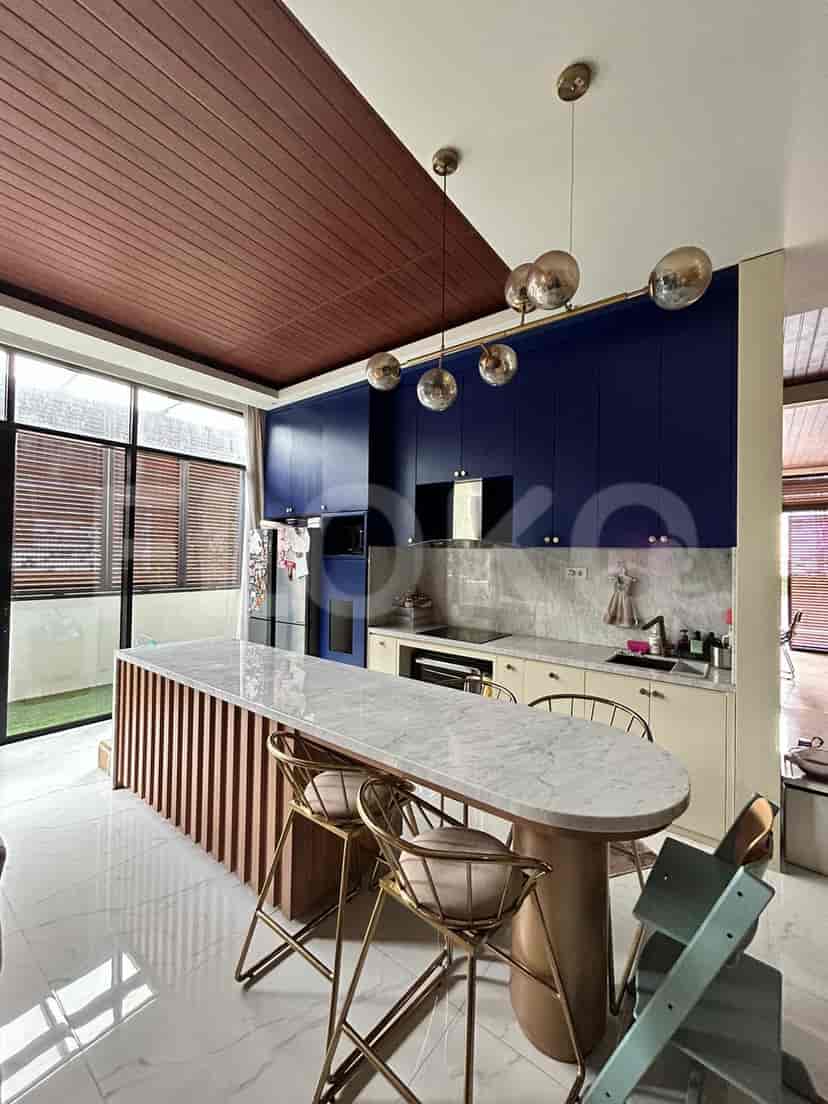 A modern kitchen with a large island, pendant lights, and dark blue cabinets.