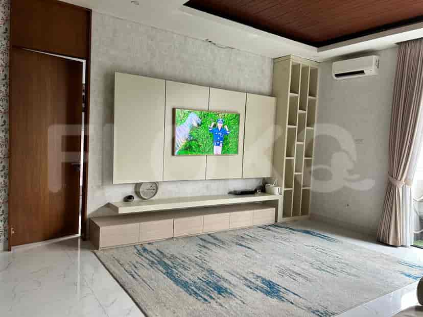 A living room with a large wall-mounted TV, built-in cabinets, and a patterned rug.