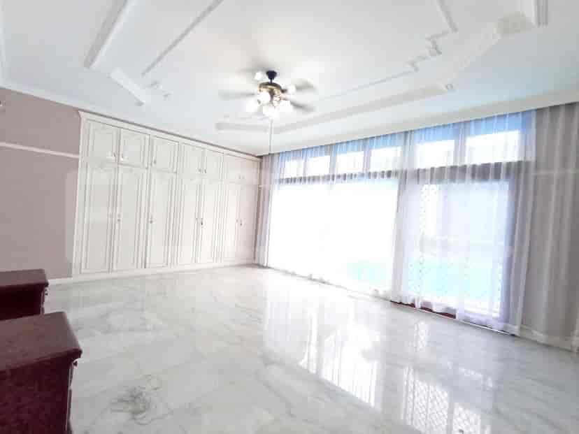 A master bedroom with white built-in wardrobes, large windows, and marble flooring.