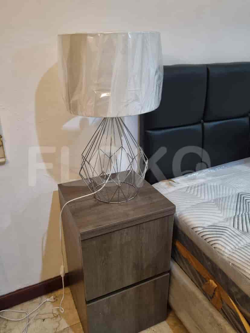 A close-up of a lamp on the nightstand in a bedroom.