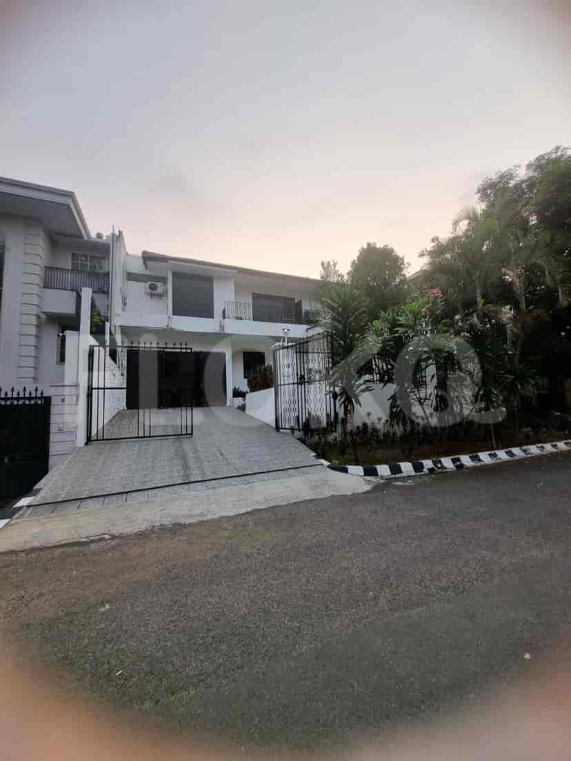 A two-story white house with a gated driveway, surrounded by trees and landscaping.