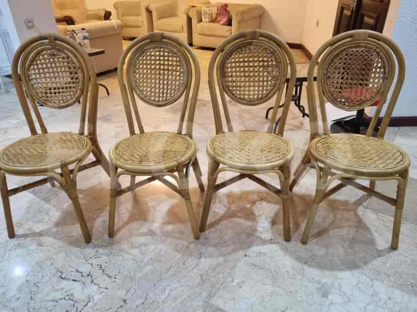 A dining room with four wooden chairs with woven seats.