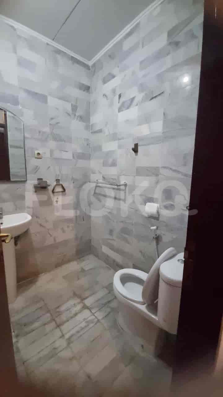 A bathroom with a toilet, a sink, and marble tiles.