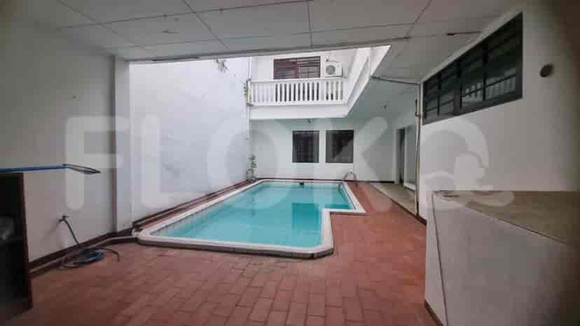 A swimming pool area with a pool, brick flooring, and a view of the house.