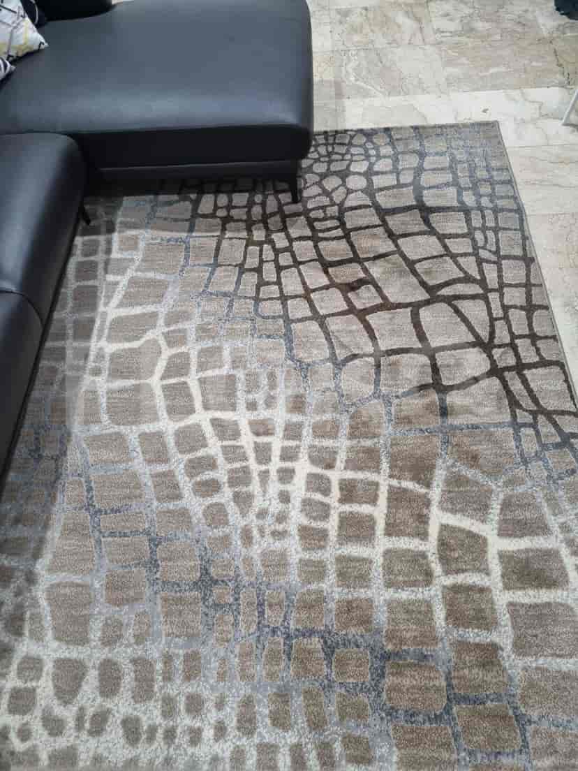 Close-up of a rug with a geometric pattern and various shades of brown and beige.
