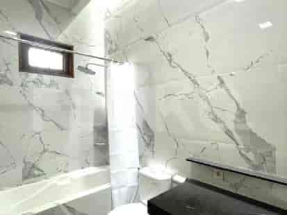 Bathroom with a bathtub, toilet, and marble tile.