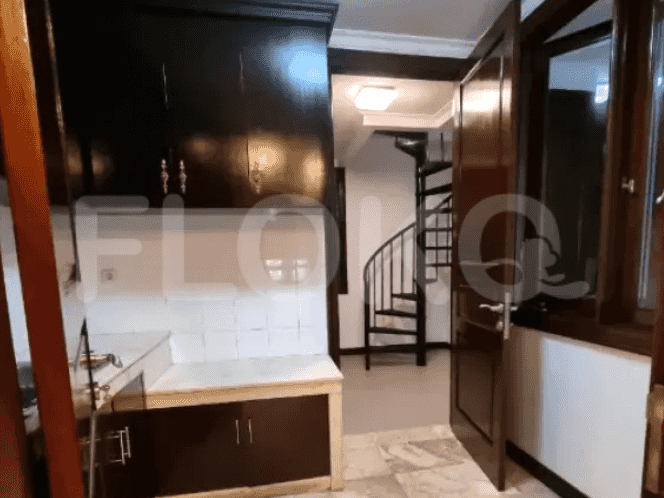 A kitchen with dark wooden cabinets, a small sink, and a spiral staircase leading to upper levels.