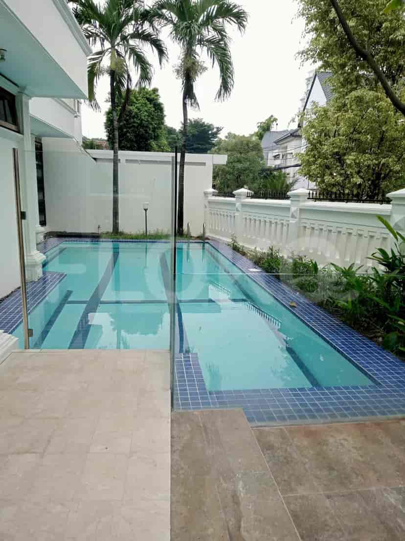 A rectangular swimming pool with a glass fence and a paved area.