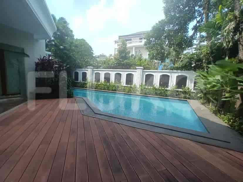 A swimming pool area with a wooden deck and a view of the garden.