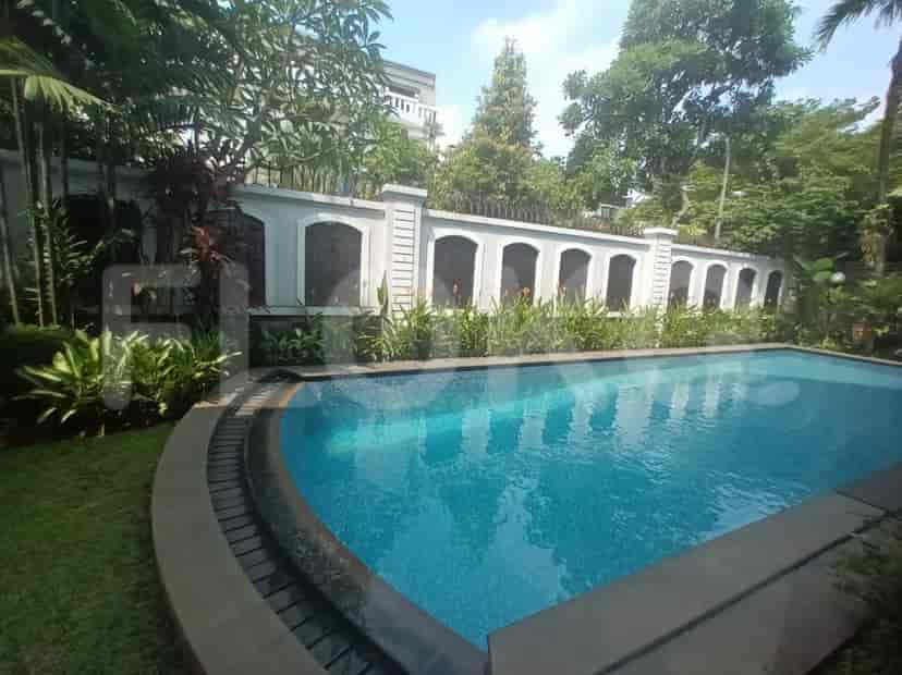 A swimming pool with wooden decking and garden area.