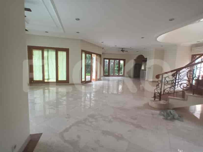 A large living room with marble flooring, high ceilings, and a staircase.