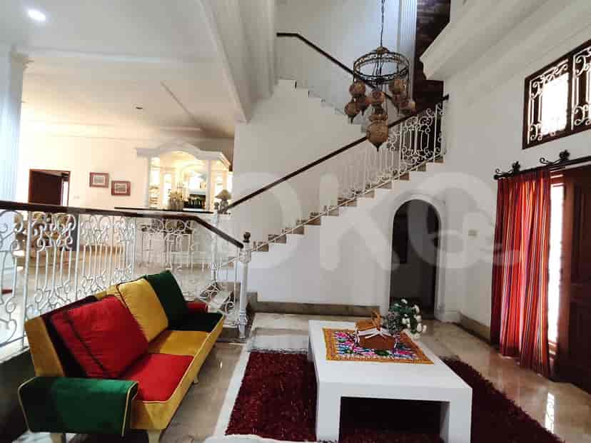 A living room featuring a colorful sofa, chandelier, and staircase.