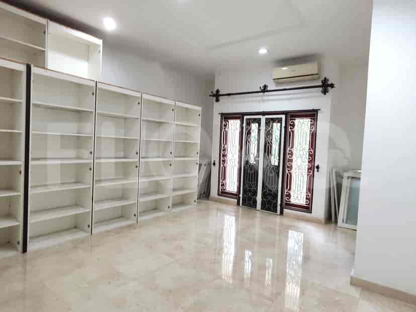 A spacious room with several built-in white cabinets and large windows.