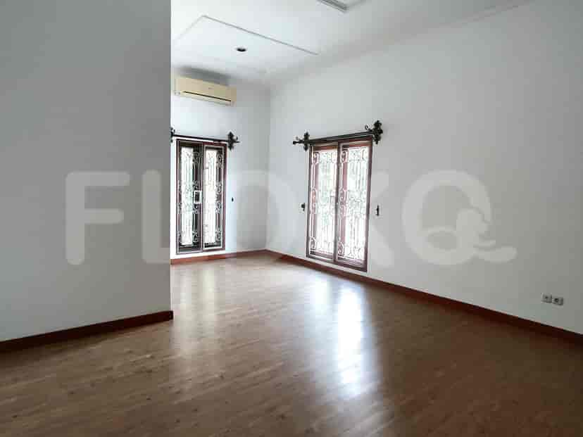 A spacious room with large windows and light wooden flooring.