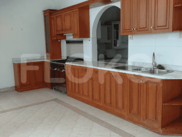 A well-lit kitchen with wooden cabinets, marble countertops, and a gas stove.
