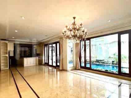 A spacious living room with marble flooring, a chandelier, large windows, and a view of a swimming pool.