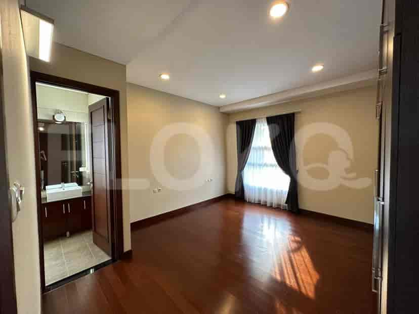 A spacious bedroom with dark wooden flooring, an attached ensuite bathroom, and a wardrobe.