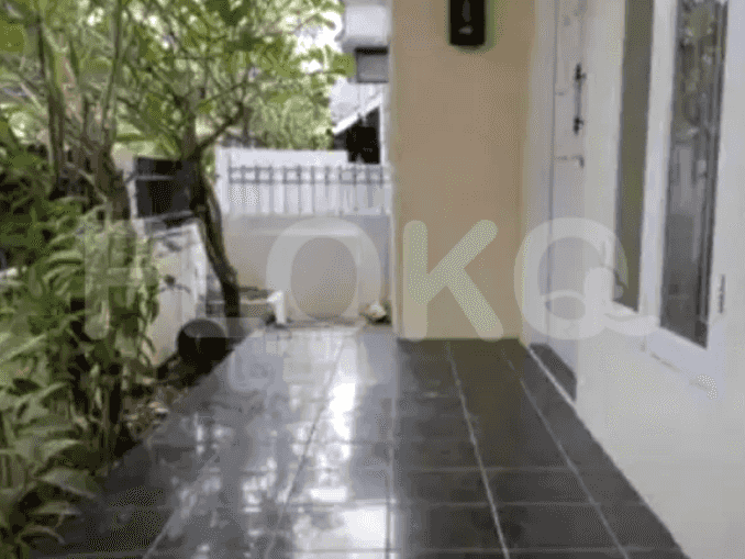 The entrance area with black tiled floors, a side garden with a small tree and a white door.