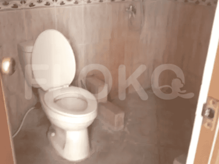 A small bathroom with a white toilet, tiled walls, and a shower area.