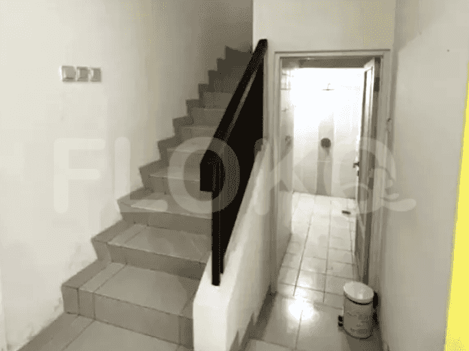 A staircase leads upstairs, with a dark wooden handrail and tiled steps, adjacent to a bathroom and a door.