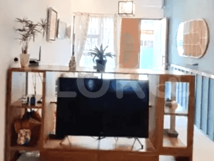 Living room with a large wooden cabinet with a TV, plants, and decorative elements, and access to the balcony.