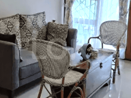 A living room featuring a gray sofa, wicker chairs, and a wooden coffee table with decorative items.