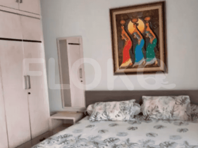 A bedroom with a double bed, a painting on the wall, and a wardrobe.
