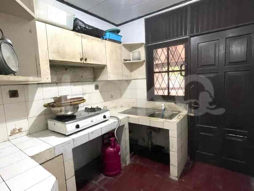 An older kitchen with a gas stove, white tiled counters, and a dark door.