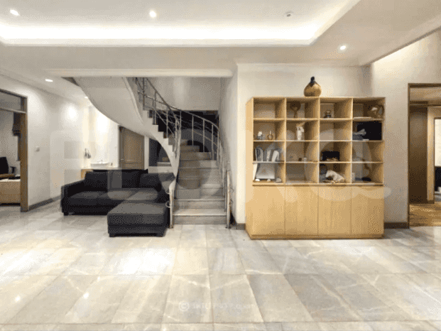 A spacious living room with an L-shaped grey sofa, a spiral staircase, and a large built-in wooden cabinet.