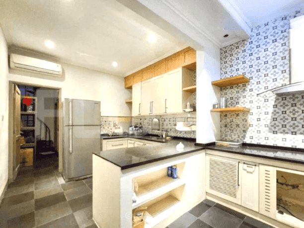 A modern kitchen with white cabinetry, black countertops, and a stainless steel refrigerator.