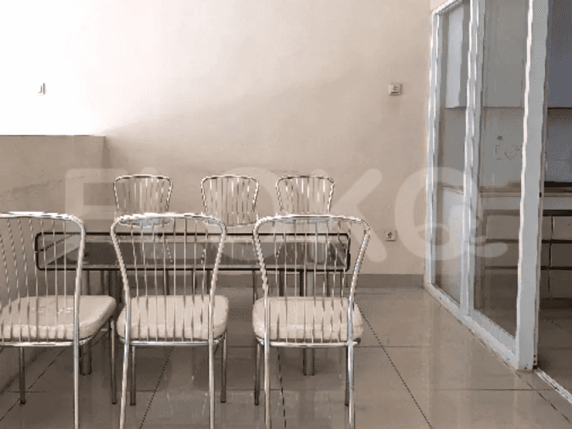 A dining area with a glass table and chairs, situated on a tiled floor.