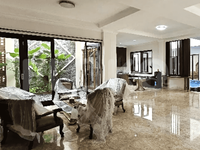 A large, bright living room with marble flooring, floor-to-ceiling glass doors leading to an outdoor area, and white walls.