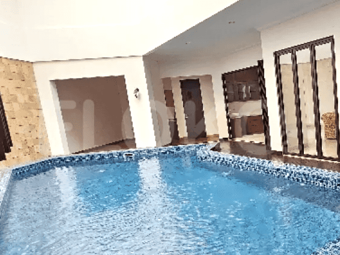 An outdoor swimming pool with a tiled surround and a glimpse of the house's exterior.