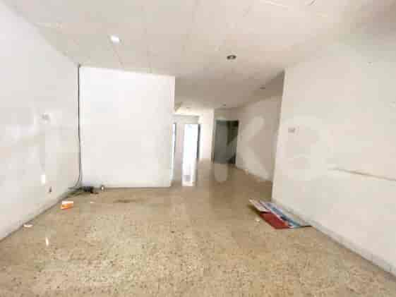 An empty room with light colored flooring and white walls, leading to other areas.