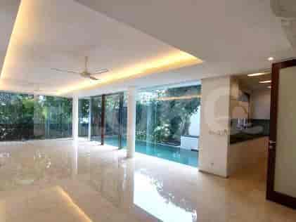 A spacious living room with large glass windows, a neutral color scheme, and a view of a garden and pool area.