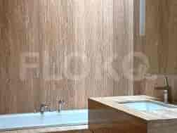 A modern bathroom with a bathtub and a light colored stone-like wall.