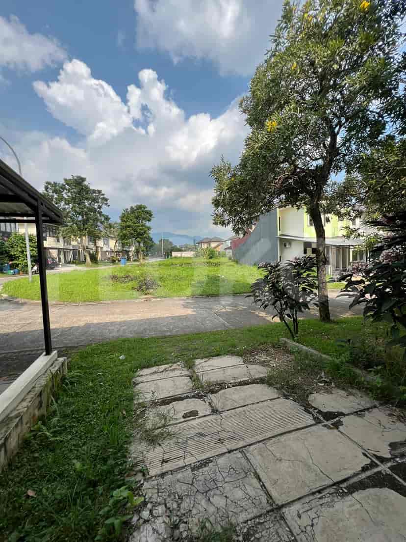 A view from the side of the house towards the open green space, with blue sky.