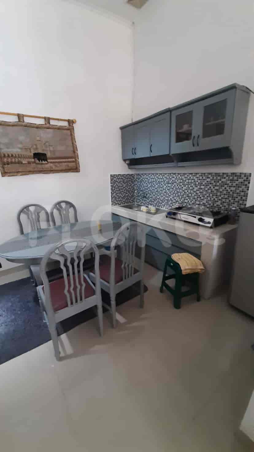 A kitchen with grey cabinets, a dining table, and a refrigerator.
