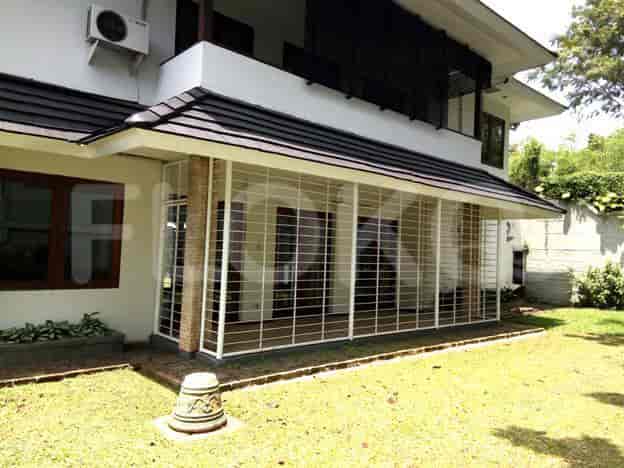 A side view of the house featuring a covered patio with white metal frame and a stone-like accent wall.