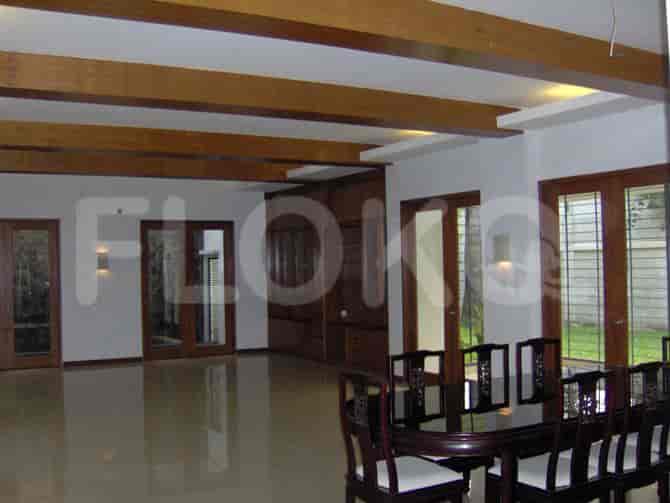 A dining room featuring a long wooden table with chairs, wooden beam ceilings, and a view to the outdoors.