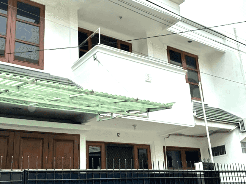 Exterior view of a two-story white house with a balcony and wooden doors.