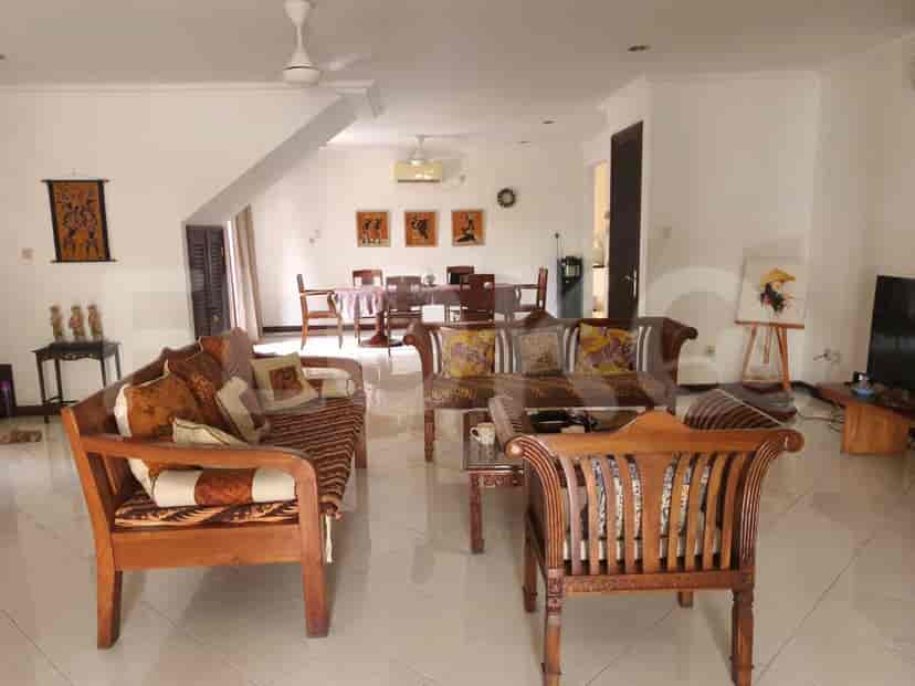 Spacious living room with wooden furniture, white tiled floors, and a high ceiling.
