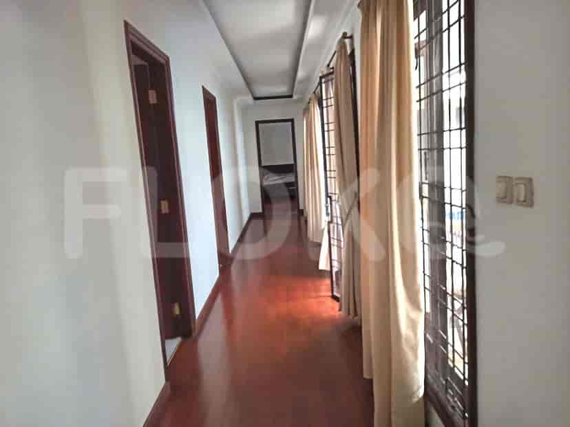 A long hallway with dark wooden flooring, white walls, and doors leading to rooms.