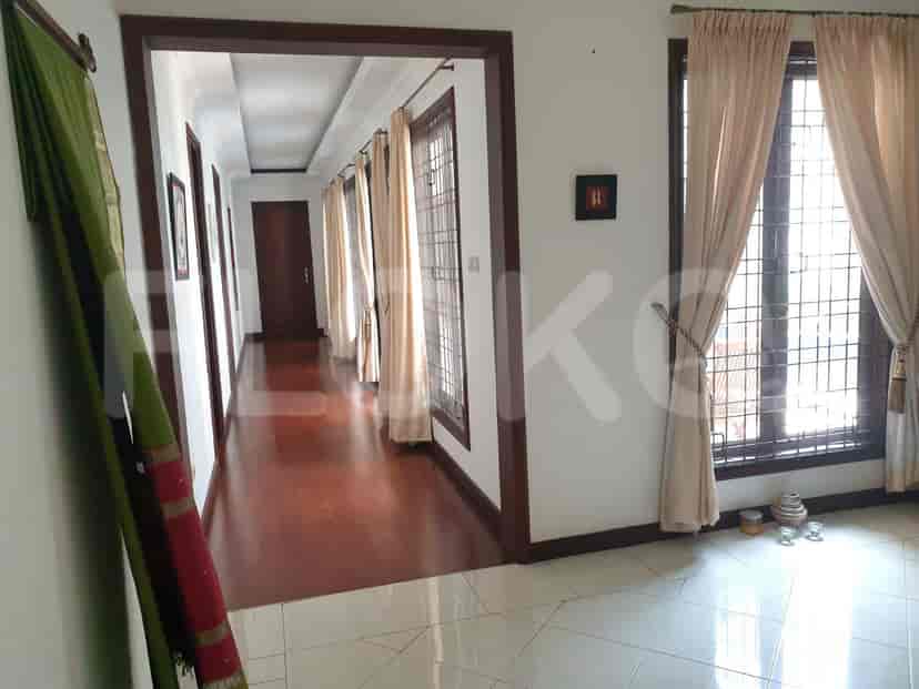 A hallway with wooden flooring, beige curtains, and doors leading to rooms.