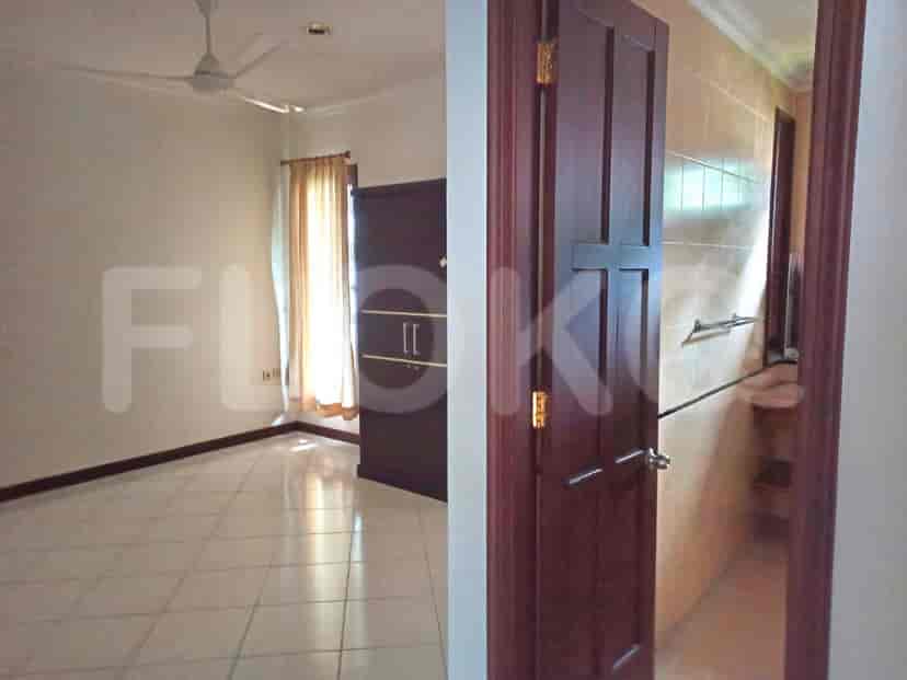 A bedroom with tiled floors, a large wardrobe, and a view of the bathroom.